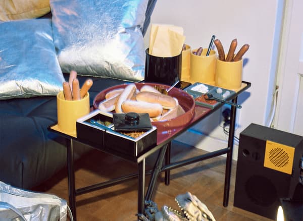 Un poggiapiedi nero con due cuscini color argento e un tavolino con articoli per la tavola modulari - IKEA