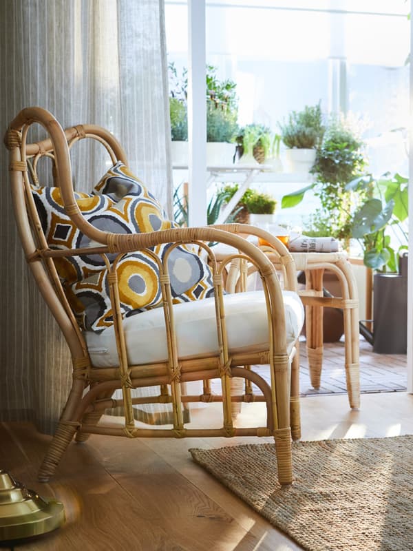 Un poltrona da interno/esterno con dei cuscini all'interno di un salotto con vista su un balcone.