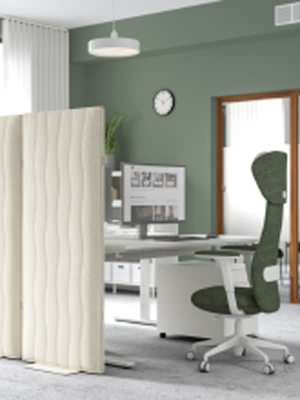 Un poste de travail dans un bureau moderne aux murs verts. Il est équipé de deux panneaux acoustiques MITTZON Gunnared beige.