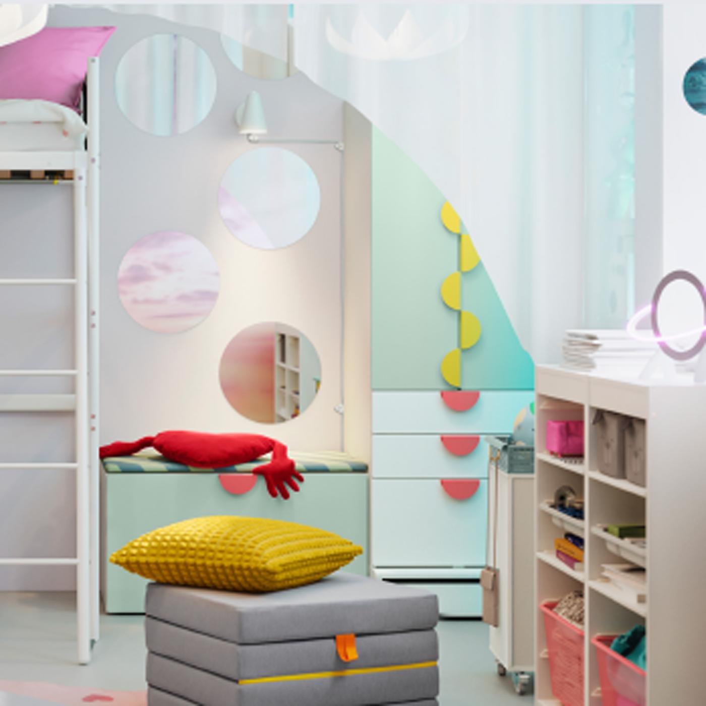 Un pouf/matelas pliant est disposé devant un rangement SMÅSTAD/PLATSA avec banc, dans une chambre d’enfant.