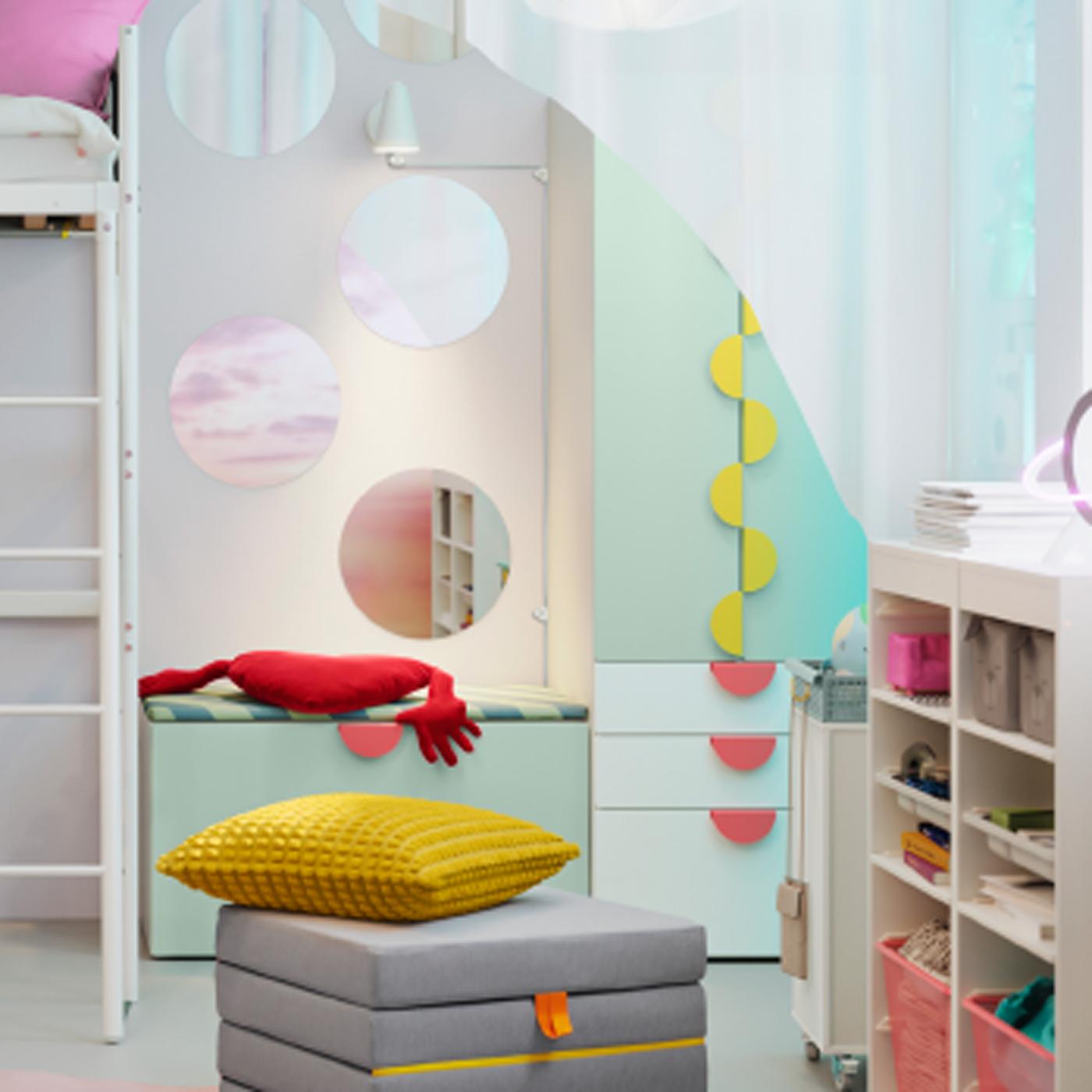 Un pouf/matelas SLÄKT pliant est disposé devant une combinaison de rangement SMÅSTAD/PLATSA avec banc, dans une chambre d’enfant.