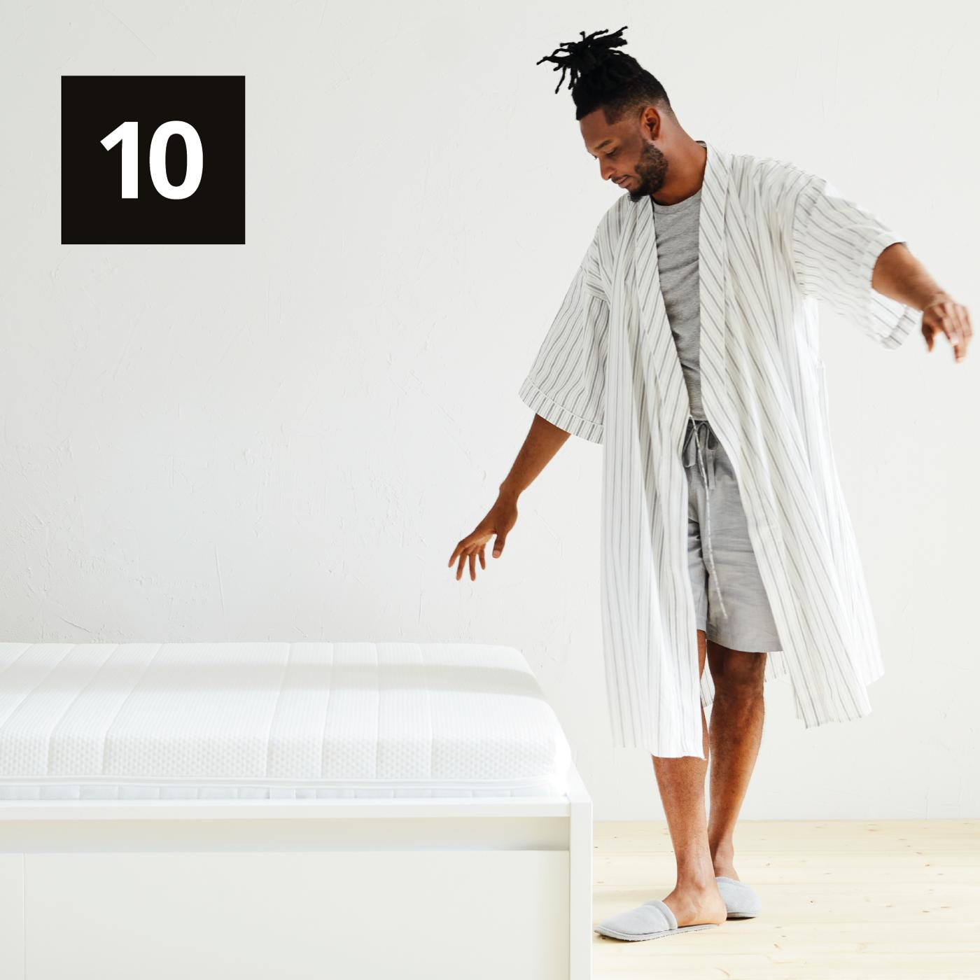 Un ragazzo cammina accanto ad un letto MALM bianco con materasso