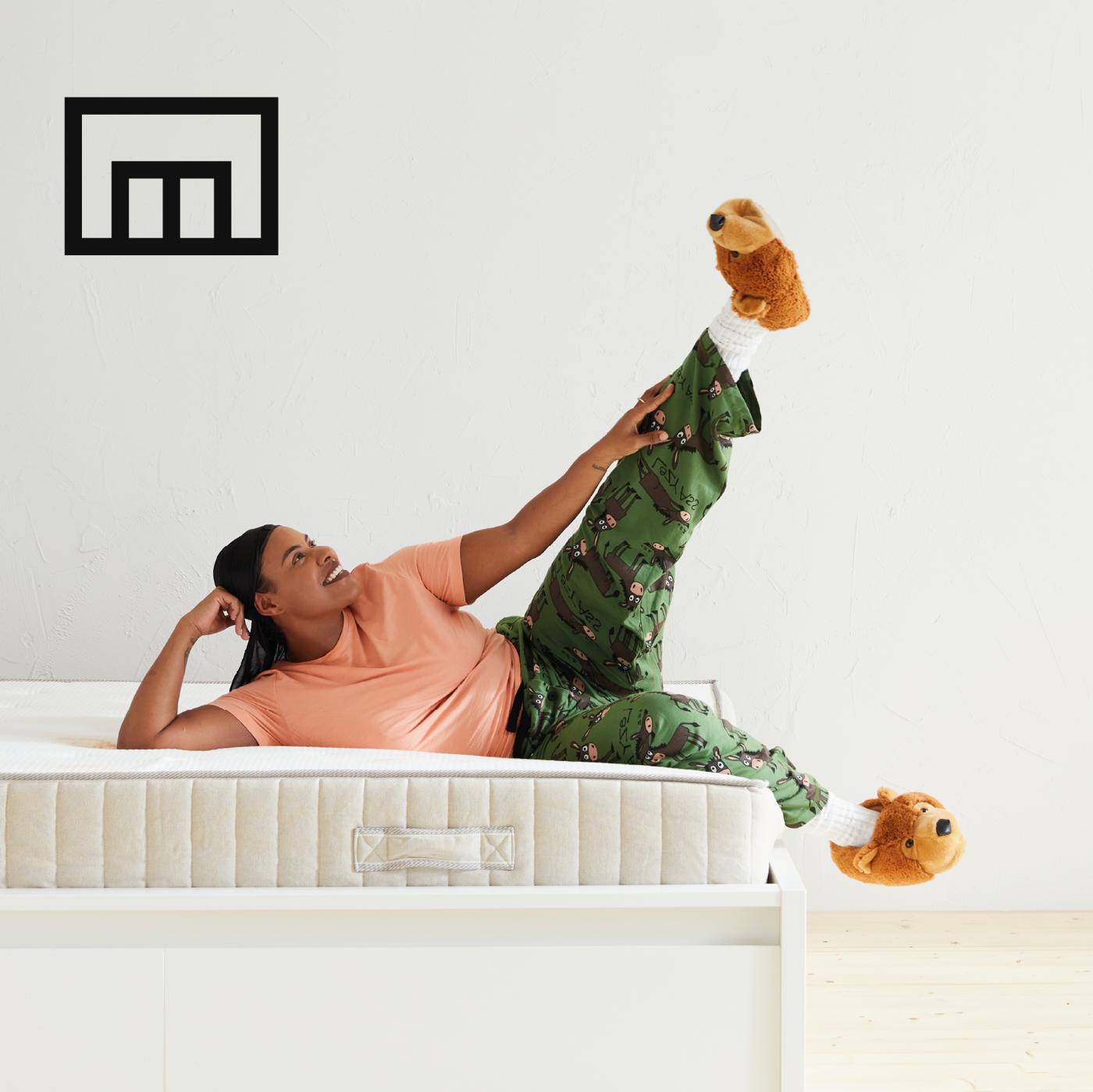 Un ragazzo in pigiama e pantofole è sdraiato sul letto MALM bianco.