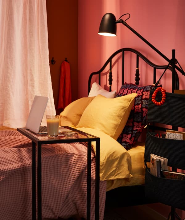 Un rideau sépare un grand lit dont une partie fait office d'espace de travail.