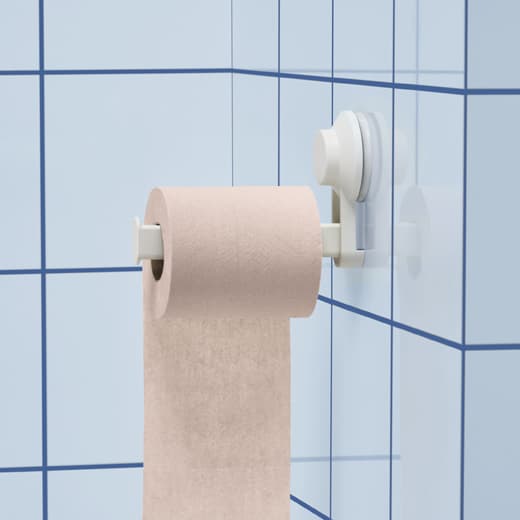 Un rolo de papel hixiénico rosa nun soporte con ventosas nunha parede azulexada en azul.