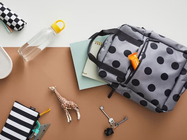 Un sac à dos STARTTID est posé à côté d’une bouteille d’eau FORMSKÖN et d’un contenant alimentaire HALVVARM, d’un sac pour accessoires SKÖRDA et d’autres articles.