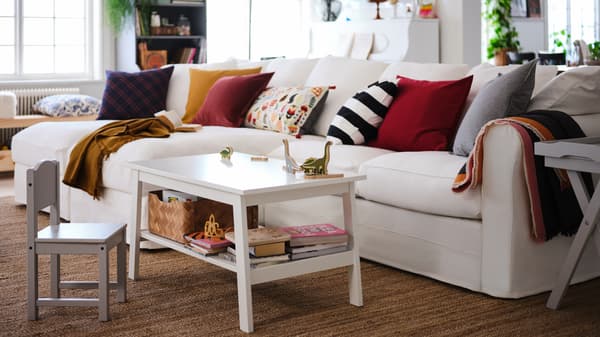Un salon avec un canapé 4 places avec méridiennes GRÖNLID blanc et une table basse LUNNARP blanc à côté.