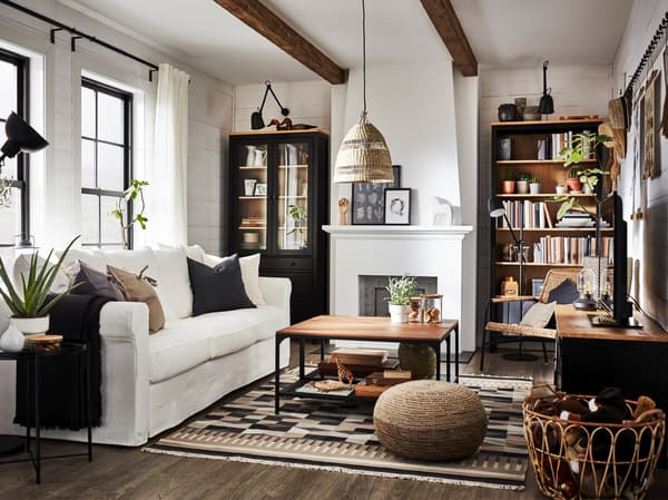 Un salon de style traditionnel meublé avec une bibliothèque, un meuble télé, un canapé blanc et une vitrine.