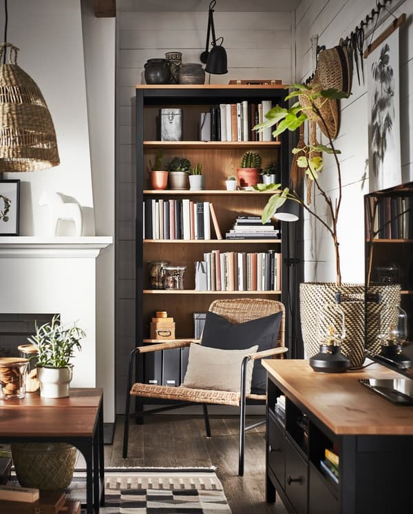 Un salon où se trouvent un meuble télé, une bibliothèque, un fauteuil en rotin et des articles en matériaux naturels.