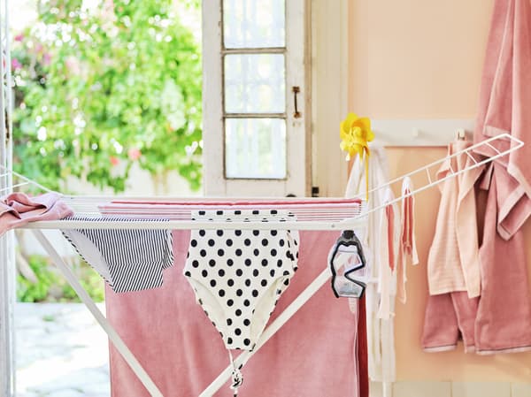 Un séchoir blanc sur lequel sèche du linge couleur corail, noir et blanc. Un masque de plongée y est également suspendu.