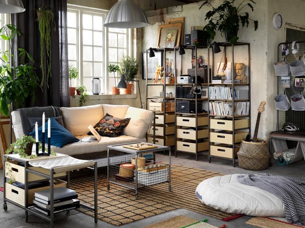 Un séjour décontracté et éclectique avec des plantes, de grandes fenêtres et des meubles de rangement en bois et en métal de style industriel.