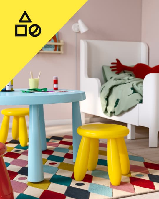 Un set se muebles infantiles de plástico sobre un tapete para niños.