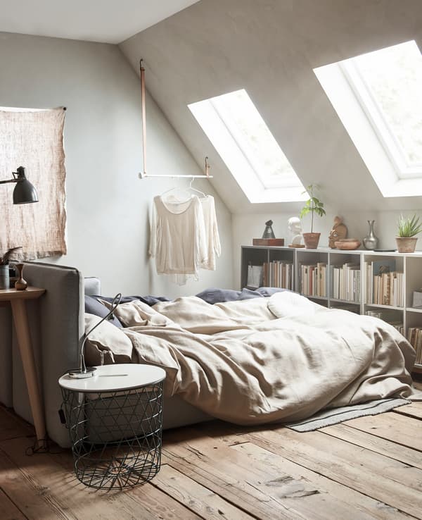 Un sofá cama aberto con roupa de cama de cores neutras.
