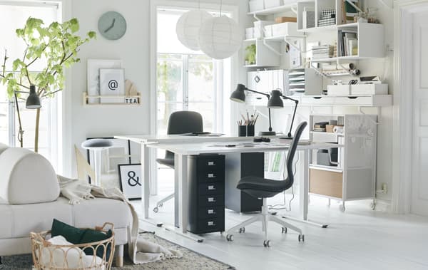 Un soggiorno bianco con scaffali da parete, due scrivanie MITTZON e due sedie da ufficio FLINTAN - IKEA