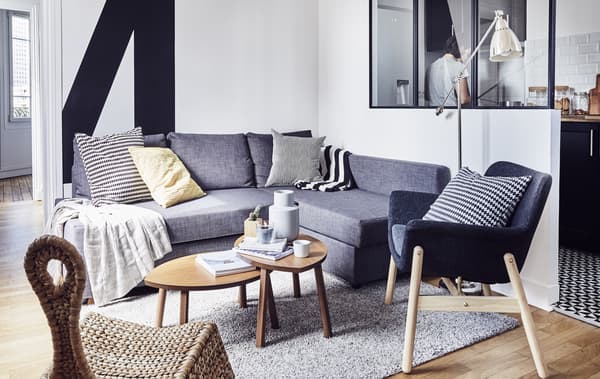 Un soggiorno bianco con un divano angolare blu, una poltrone e una poltroncina a dondolo in rattan