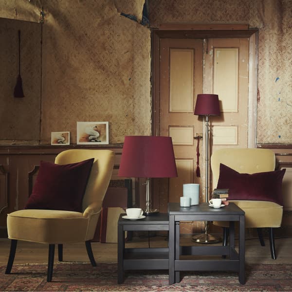 Un soggiorno con poltrone gialle, cuscini in velluto e un set di tavolini impilabili HAVSTA.