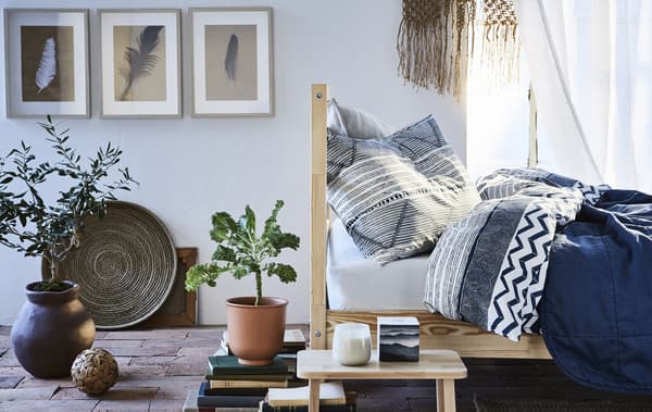 Un soggiorno con tessili blu, mobili in legno chiaro e accessori in terracotta - IKEA
