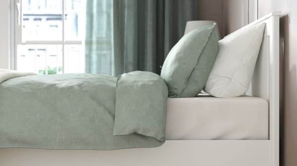 Un struttura letto SONGESAD con cuscini verdi e bianchi e una piumino verde. 