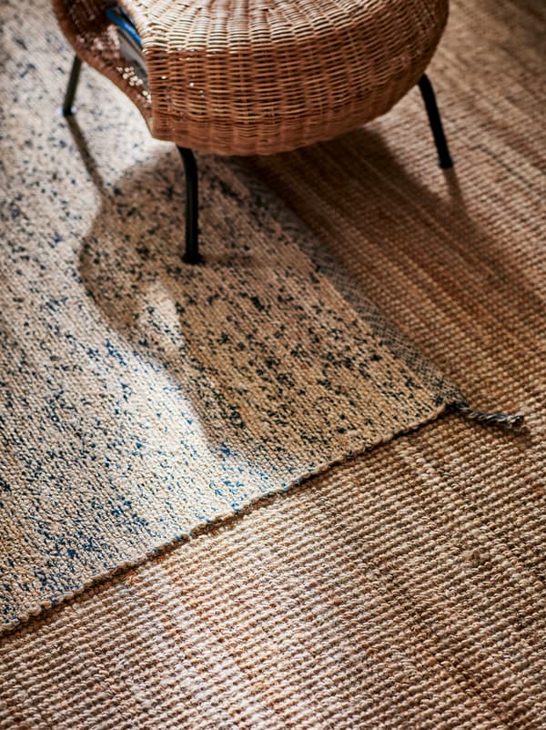 Un taburet cu spațiu de depozitare GAMLEHULT, care este așezat pe un covor din iută MELHOLT bej care la rândul său este întins peste un alt covor maro deschis.