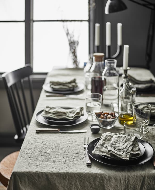 Un tavolo da pranzo rustico moderno con una tovaglia in lino, un mix di sedie diverse e stoviglie moderne - IKEA.