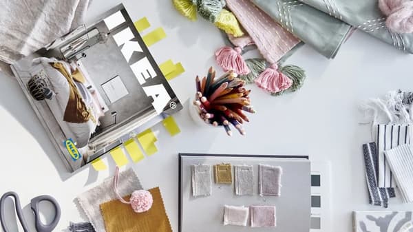 Un tavolo visto dall'alto con sopra un catalogo IKEA e diversi quaderni e accessori.