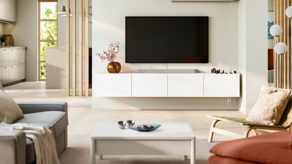 Un televisione con sotto una mobile tv BESTÅ attaccati alla parete.