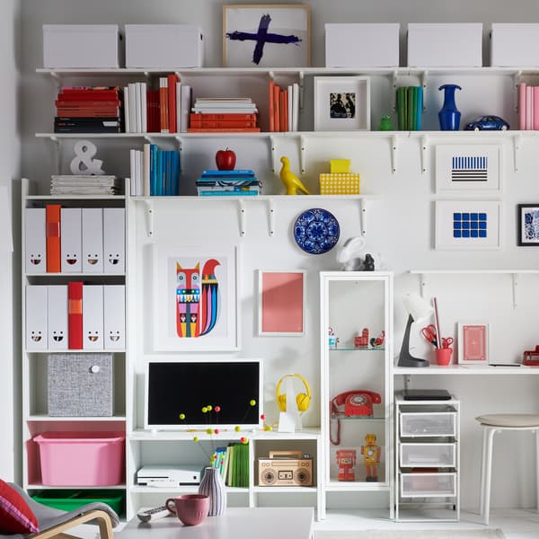 Un televisor sobre un mueble de TV BAGGEBO blanco contra una pared blanca y rodeado de otros muebles de almacenaje de la serie BAGGEBO.