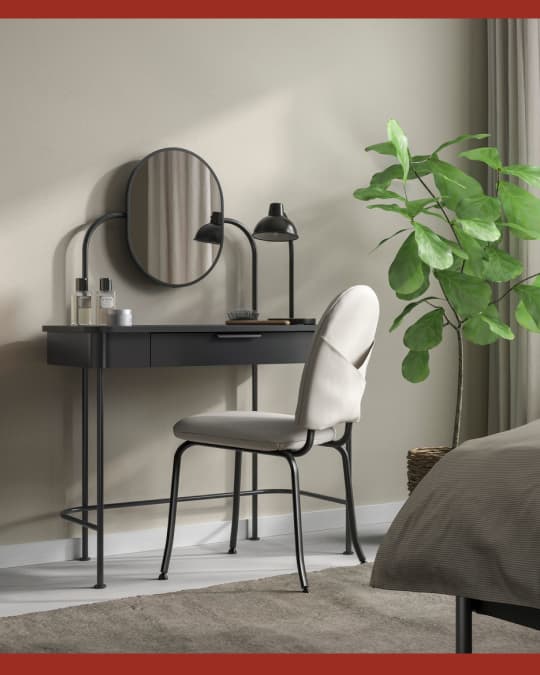 Un tocador IKEA con un espejo evalado en la esquina de un dormmitorio matrimonial.