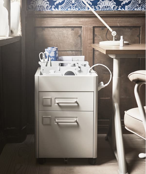 Un ufficio con carta da parati a fantasia blu, una cassettiera, una scrivania e una scrivania.