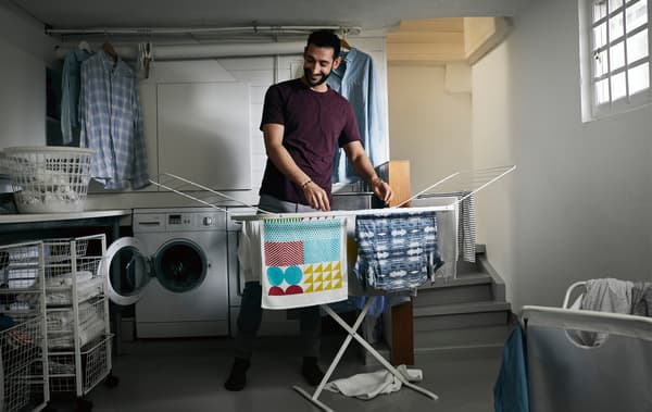 Un uomo stende il bucato in un locale lavanderia - IKEA