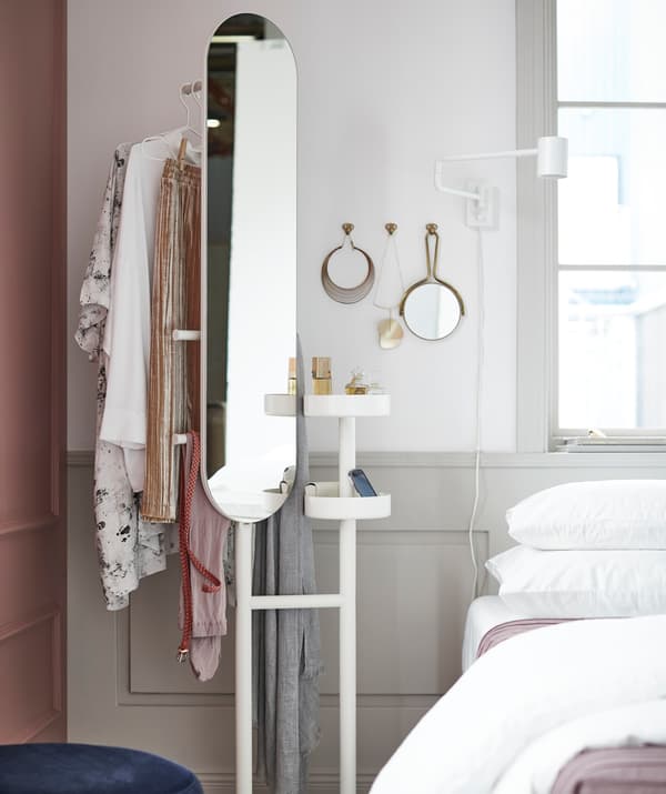 Un valet avec miroir IKEA LIERSKOGEN à côté d’un lit.
