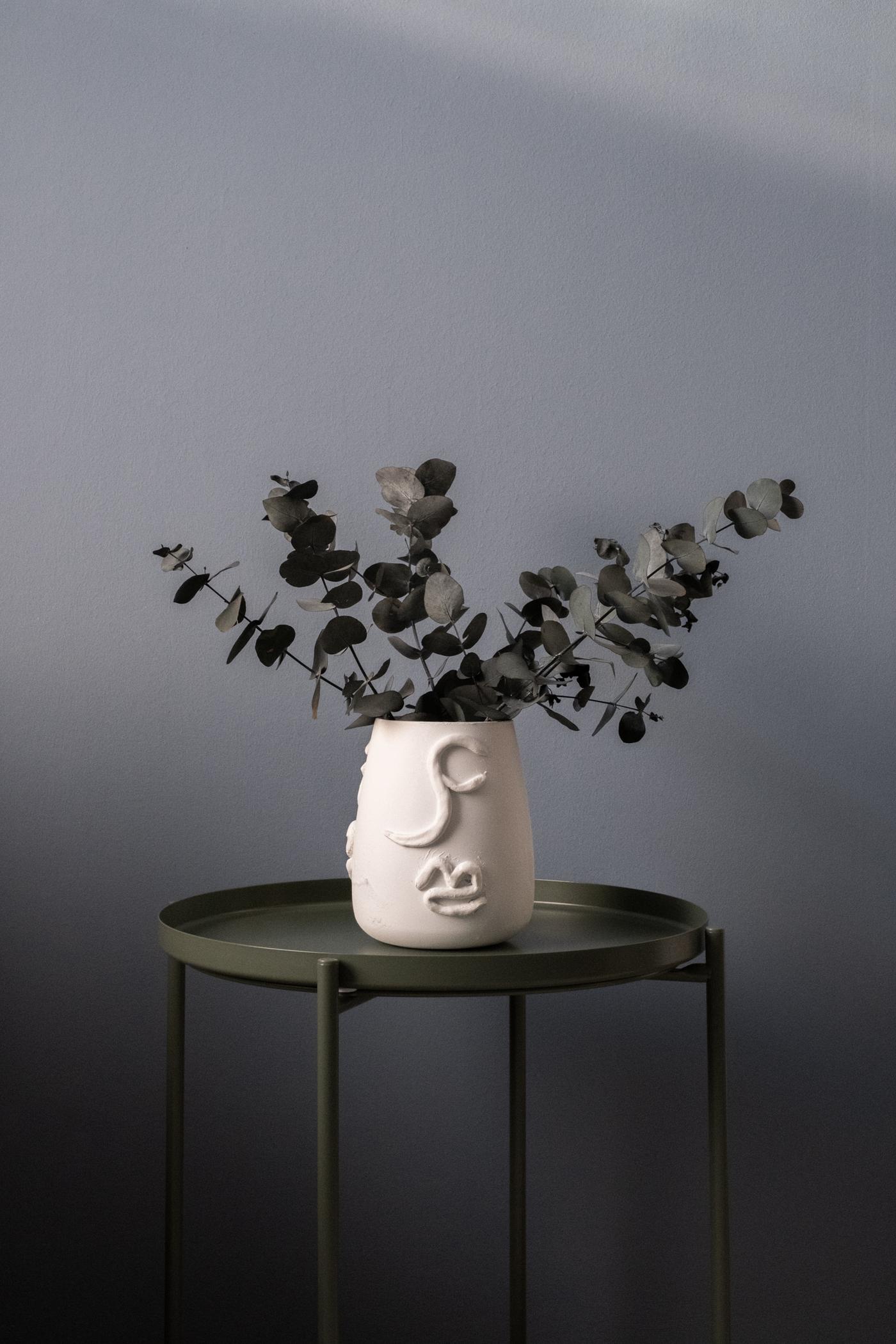 Un vase en terracota sur une table d'appoint verte