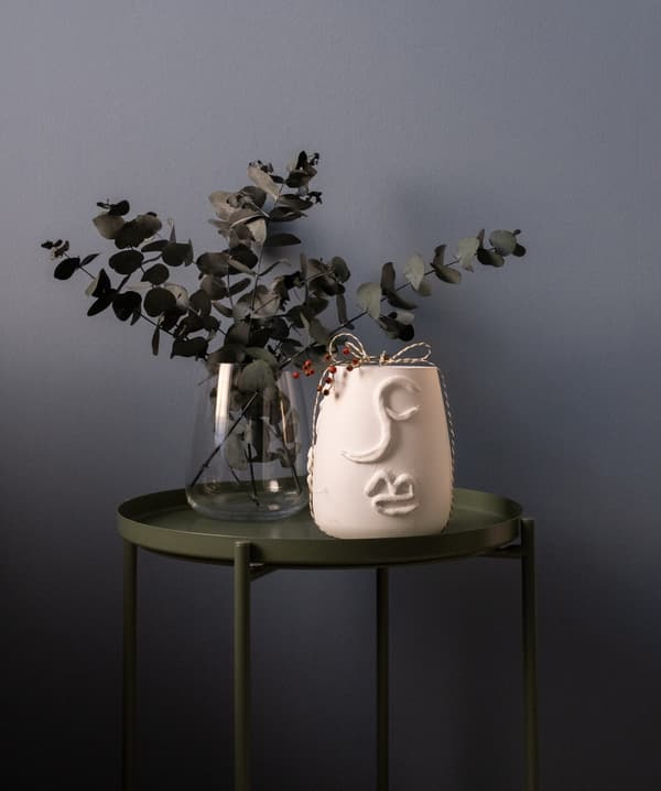 Un vase en verre avec de l'Eucalyptus et un vase en terracota sur une table d'appoint verte