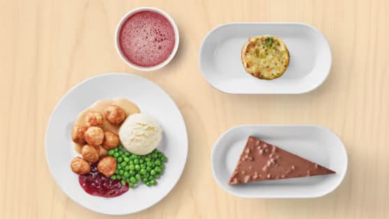 Un vassoio con quattro di piatti con polpette vegetali, medaglione di verdure, bibita alla spina e torta Daim.