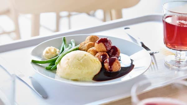 Un vassoio con un piatto di polpette svedesi con contorno di purè, salsa e fagiolini.