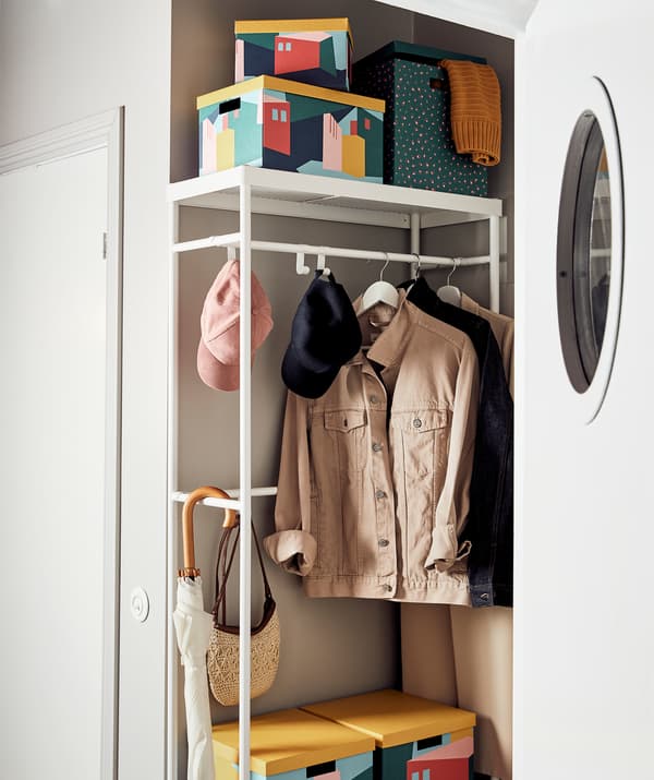 Un vestibule avec un portemanteau MACKAPÄR. En plus des vestes et des accessoires, le portemanteau est rempli de différentes boîtes TJENA.