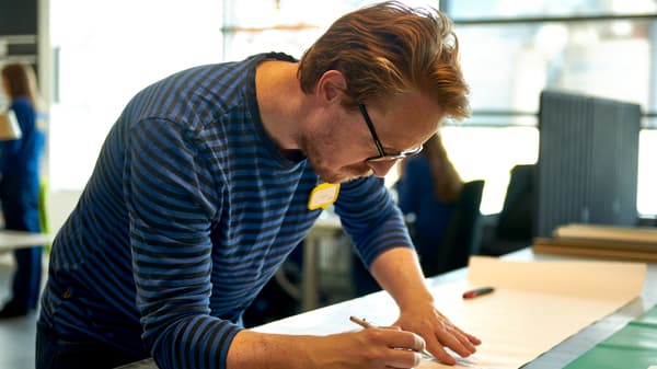 Un visual merchandiser IKEA réalise une esquisse, debout à un bureau.