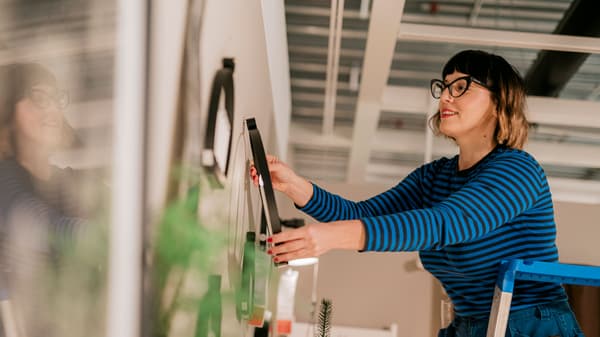 Un visual merchandiser IKEA stă la un birou și realizează o schiță.