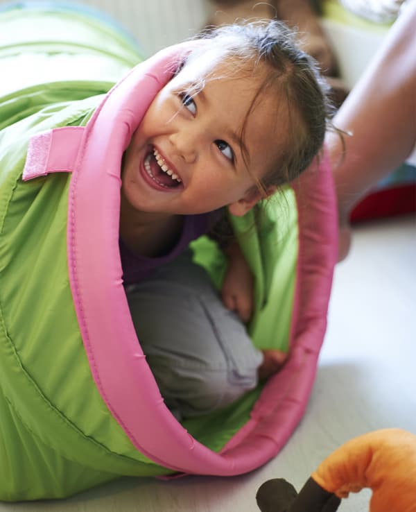 Una bambina in un tunnel da gioco.