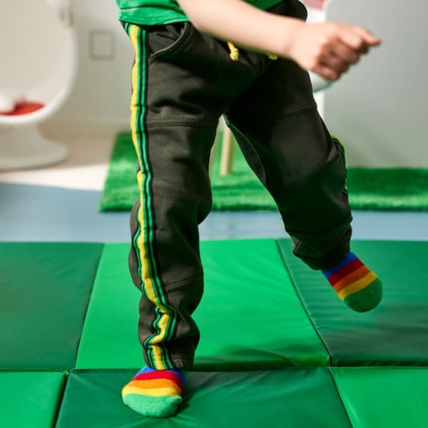 Una bambino gioca su un tappeto gioco verde.