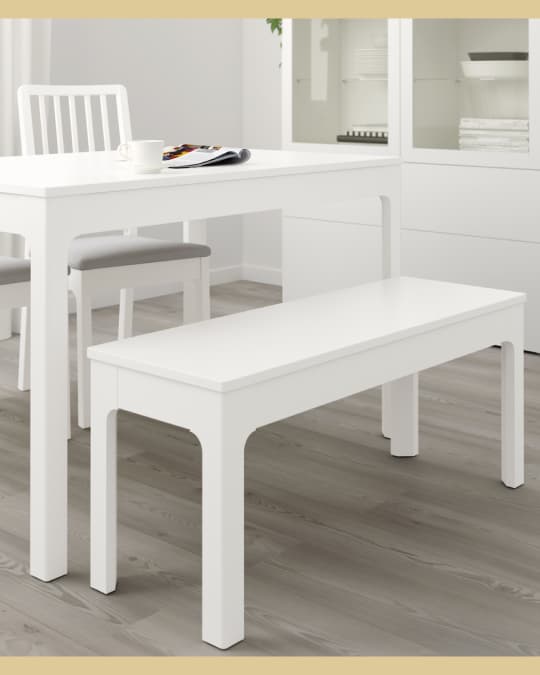 Una banca de madera blanca frente a una mesa de comedor rectangular.