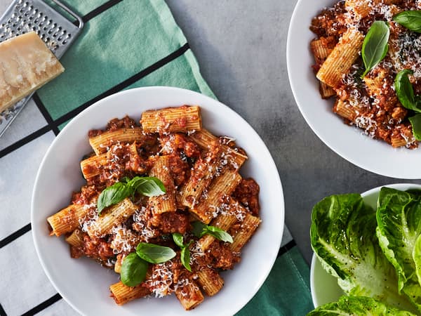 Una boloñesa italiana clásica hecha de carne molida de origen vegetal, servida en tazones blancos.