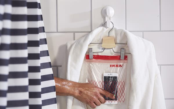 Una bossa de tancament plàstic, penjada d’un penja-robes, coberta amb un barnús i utilitzada com a suport per al telèfon mòbil.