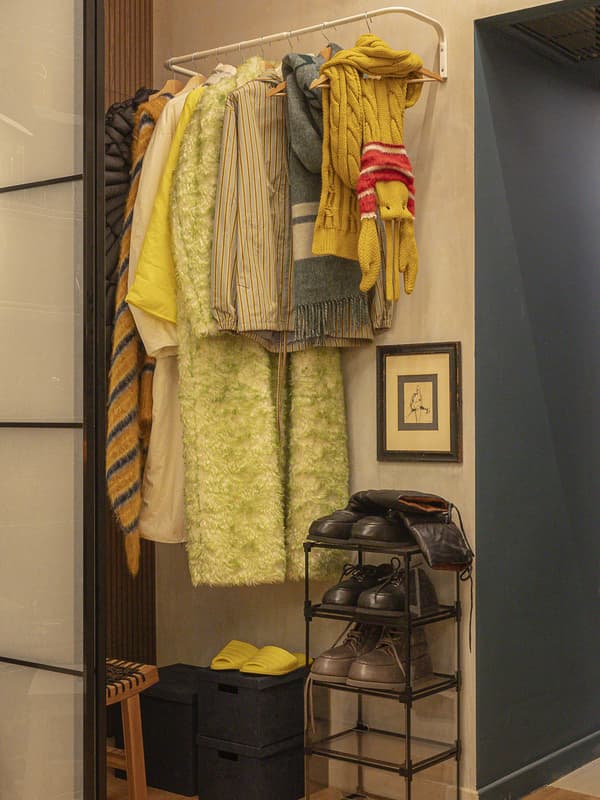Una cabina armadio creata da una porta scorrevole che separa uno spazio comune da uno più intimo in cui sono presenti vestiti e scarpe.