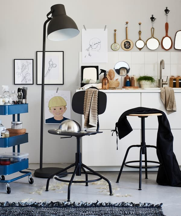 Una cadira giratòria IKEA KULLABERG envoltada de material de perruqueria i un llum de peu per tallar-se els cabells a casa.
