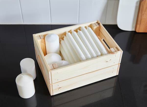 Una caixa de pi IKEA KNAGGGLIG per guardar espelmes blanques.