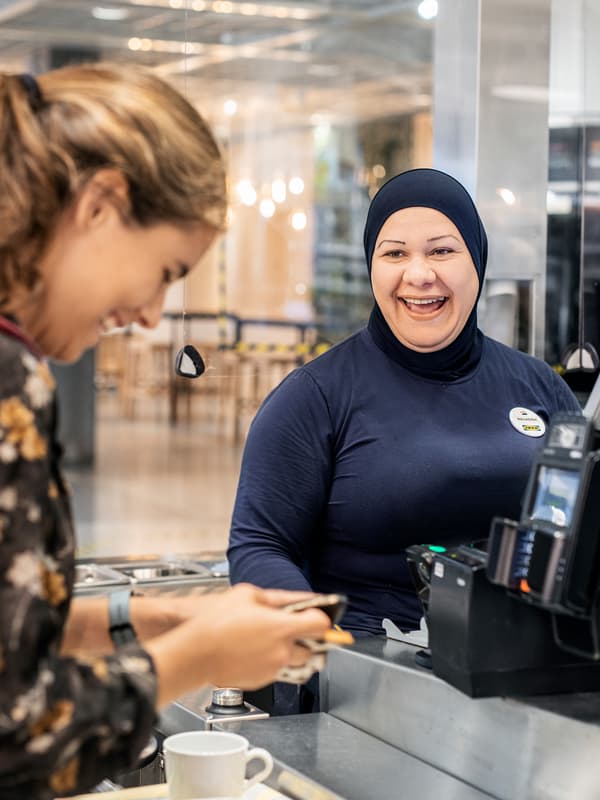 Una caixera d'IKEA amb un hijab fent broma amb una clienta a la caixa.