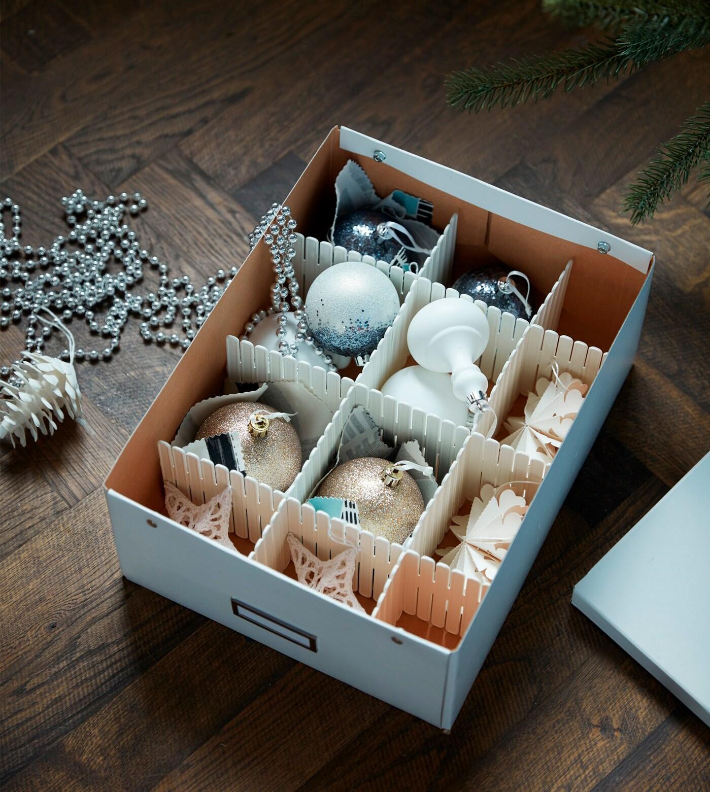 Una caja de cartón con una rejilla armada con cartones. Dentro de la rejilla hay decoraciones navideñas.