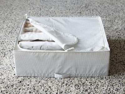 Una caja STUK con cierre y ropa de cama en el interior.
