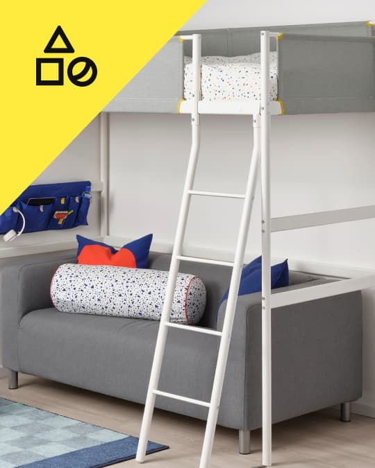 Una cama alta infantil y en la parte de abajo un sofá con textiles para niños.